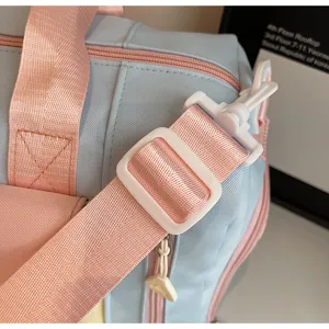Close-up detail shot of the durable pastel blue and pink travel bag strap and buckle.