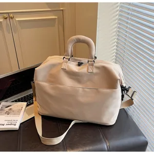 Détail en gros plan du sac de voyage beige avec bandoulière et grande capacité pratique.