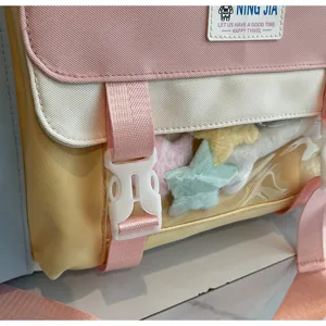 Sweet color-block travel backpack with clear pocket and plush star charms for daily use.