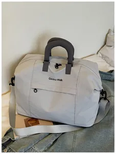 Close-up detail of the light gray travel duffel bag showing durable fabric and zippers.