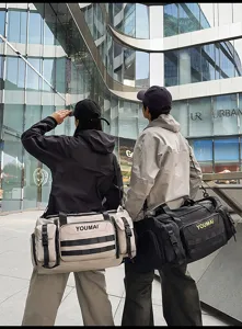 Detail view of multi-pocket travel duffel bag with shoulder strap in outdoor setting.