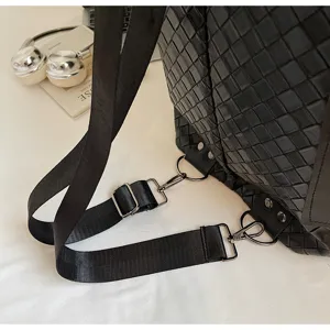 Dettaglio zaino in pelle intrecciata nera con spallacci regolabili e ganci metallici.