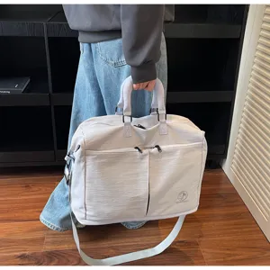 Detailed view of large capacity travel duffel bag handle and front pocket design in light grey.