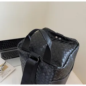 Vista dettagliata della borsa da viaggio in pelle nera intrecciata, manici resistenti.