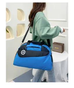 Detailed shot of a blue and black travel duffel bag worn by a model, showing shoulder strap.
