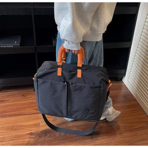 Detailed view of large capacity black travel bag with orange handles, casual style outdoor duffel.
