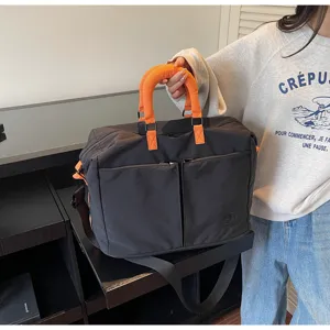 Detailed view of the large capacity travel duffel bag with bright orange handles and pockets.