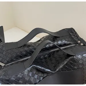 Dettaglio borsa da viaggio in pelle intrecciata nera, grande borsone uomo elegante.