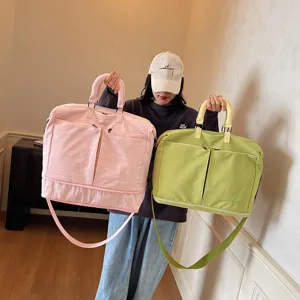 Large capacity solid color travel duffel bag with front pockets and shoulder strap.