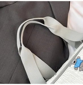 Detailopname van de reistasriem en gestructureerde witte stof met schattige berenprint.