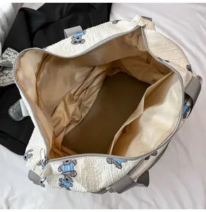 Overzicht van de grote beige reistas met schattig berenpatroon en handige zakken aan de binnenkant.