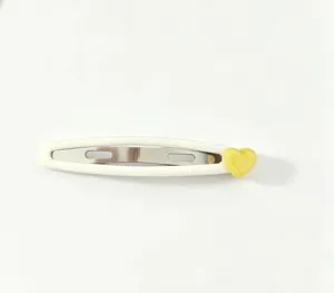 Detail shot of a cute white snap hair clip featuring a glossy yellow heart charm accent.
