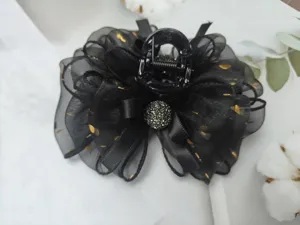Close-up of black mesh bow hair claw clip with delicate gold foil dots and sparkling center.