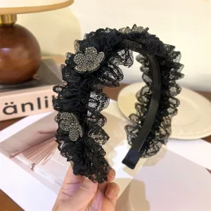 Primer plano detalle de diadema de encaje negro con flores de pedrería, elegante.