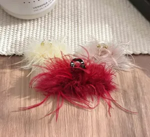 Detailed shot of fluffy feather hair claw clips in red, white and pink, elegant winter design.