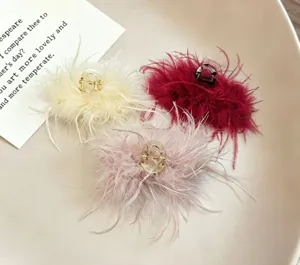 Close-up of fluffy feather hair claw clips in beige, red, and pink, elegant winter hair accessory detail.