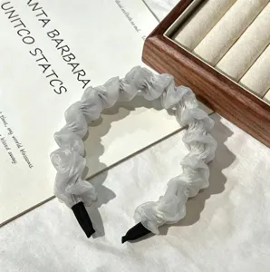 Detail shot of white chiffon ruffled hairband featuring delicate pleats and black tips.