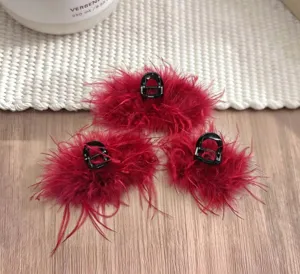 Detailed view of the red feather hair claw clip, fluffy plush design for stylish winter updo hairstyles.
