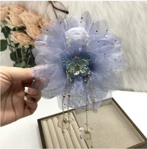 Close up detail of large purple mesh flower hair claw clip with delicate hanging gold chains.