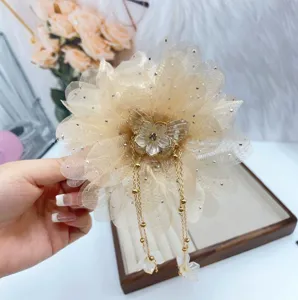 Detail shot of champagne mesh flower hair claw clip with elegant metallic tassel and butterfly.
