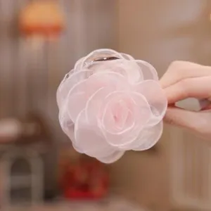 Pink sheer fabric camellia flower hair claw clip for elegant women styling and side ponytail.