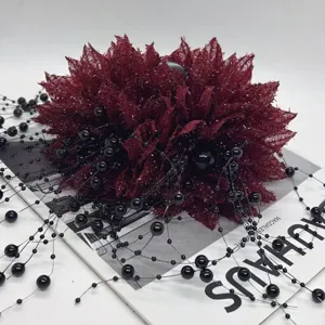 Détail de la pince à cheveux fleur en tissu rouge avec franges de perles noires.