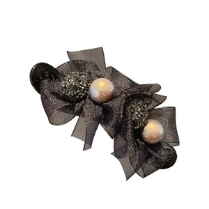 Close-up detail van grote zwarte strik haarklem met strass-steentjes en mooie parels.
