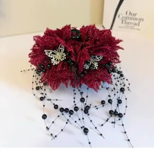 Gros-plan d'une pince à cheveux en dentelle rouge avec papillons strass et pompons perles.