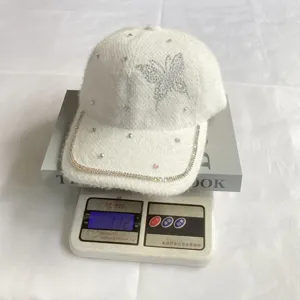 Modische weisse flauschige Baseballkappe mit Strass-Schmetterling für den Winter.