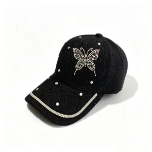 Nahaufnahme der schwarzen Strickmütze mit funkelndem Strassschmetterling und glitzernden Kristallen.
