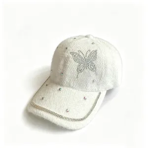 Nahaufnahme einer weißen Plüsch-Baseballkappe mit Strass-Schmetterling und Kristallkette.