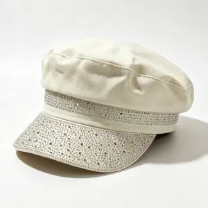 Primo piano di dettaglio del cappello militare piatto lucido decorato con strass in beige.