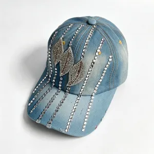 Vista detallada de la gorra de béisbol de mezclilla con pedrería y patrón de hojas de cristal.