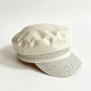 Primo piano dettagliato del cappellino écru di tendenza decorato con strass sulla visiera.