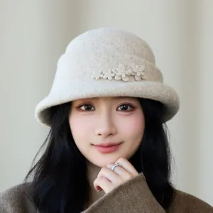 Close-up view of the beige wool bucket hat with delicate floral details worn by the model.