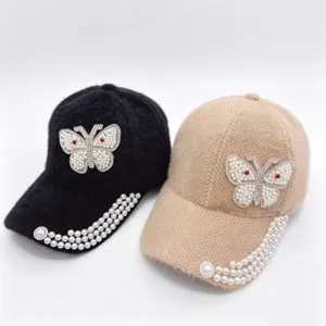 Détail de casquette de baseball en fausse vison avec papillon en perles et strass.