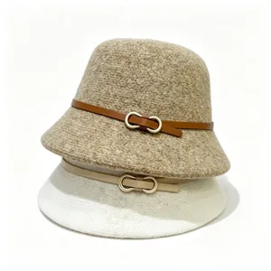 Gedetailleerd overzicht van wollen bucket hats met lederen riem en metalen gesp, gestapeld.