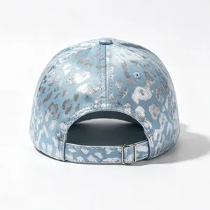 Detailed view of a stylish blue denim baseball cap featuring a shiny silver foil leopard print.