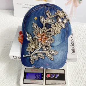 Vista dettagliata del berretto da baseball in jeans di tendenza con ricamo dorato e strass.