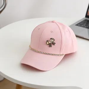Detailed close-up of the pink kids baseball cap featuring sparkling rhinestone bow and chain decor.