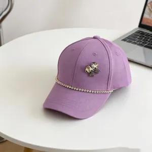 Close-up detail of a purple kids baseball cap featuring a sparkling rhinestone bow and chain.