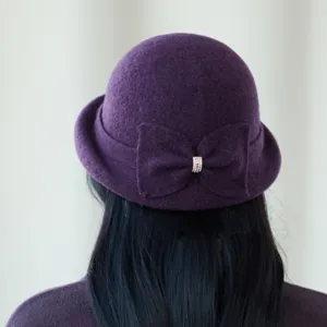 Detailed view of a purple wool blend cloche hat with an elegant rhinestone bow detail.