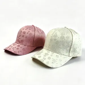 Detailed view of women's rhinestone floral baseball caps in pink and off-white colors.