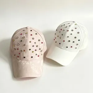 Detail van strass honkbalpet met kleurrijke kristallen op roze en witte gebogen petten.