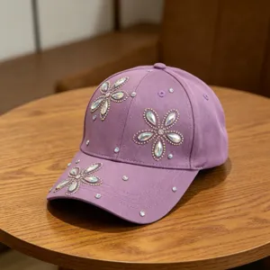 Detail kinder honkbalpet met strass bloemen, fonkelende kristallen op paarse stof.