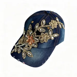 Vista dettagliata del berretto in denim blu scuro con ricamo in oro squisito e strass scintillanti.