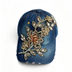 Vista dettagliata del cappello da baseball in denim strass con ricamo floreale in oro.