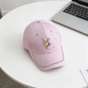 Gedetailleerd overzicht van een roze pet met fonkelende strass-steentjes en konijnenbroche.