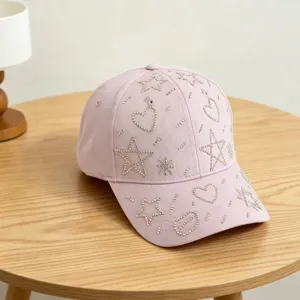 Detail van roze honkbalpet met sprankelende strass-sterren en hartjespatronen.