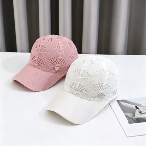 Close-up detail of knitted hollow breathable baseball caps in pink and white with heart logo.